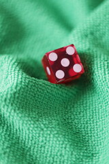 Un dado rojo para juego en una tela de color verde como fondo 