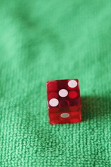 Un dado rojo para juego en una tela de color verde como fondo 