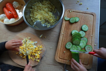 two child's hands cutting vegetables for salad close up
