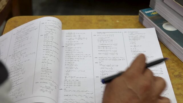 Indian student writing notes at night surrounded by books for intense study