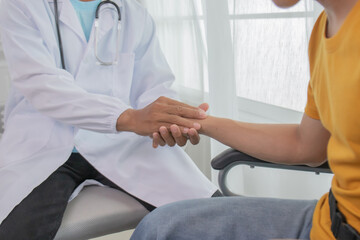 Obraz premium A male doctor in uniform examines the knee of a 30-year-old man sitting in a chair, offering comfort and advice, support and medical solutions for recovery.