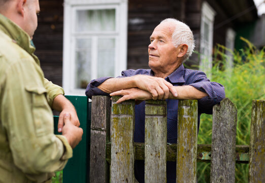 Elderly man discussing with neighbour beside house