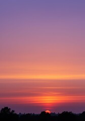 Fototapeta premium Vivid Sunset Sky with Orange and Purple Colors Over Silhouetted Trees