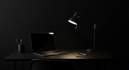 Monochrome workspace featuring a laptop, desk lamp, and stationery on a dark desk