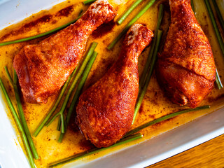 Crispy baked chicken drumsticks in baking dish on wooden table
