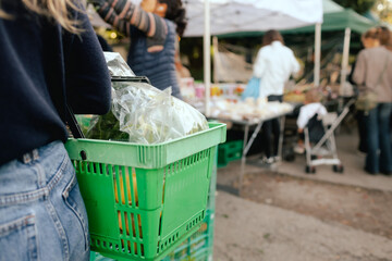 Close up of hand with a vegetables and greens in shopping basket on the local Farmers market....