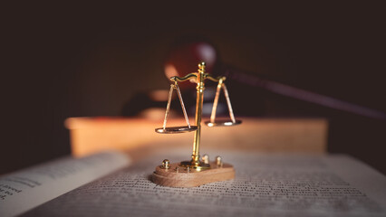 Justice scale and judge’s gavel on open law book, symbolizing judgment, law, fairness, and legal...