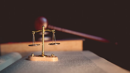 Justice scale and judge’s gavel on open law book, symbolizing judgment, law, fairness, and legal...