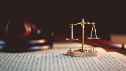 Justice scale and judge’s gavel on open law book, symbolizing judgment, law, fairness, and legal...