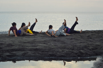 With their right legs lifted and hands placed behind them for balance, the girls gently lean back...