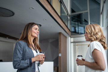 Businesswomen chatting during coffee break in modern office building