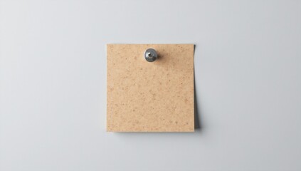Blank brown paper note pinned to a light grey wall with a thumbtack.