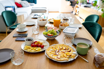 beautifully set wooden table showcases a generous brunch spread, featuring a homemade peach tart,...