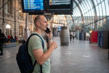 Businessman using mobile phone at train station. Handsome mature man on business trip walking with...