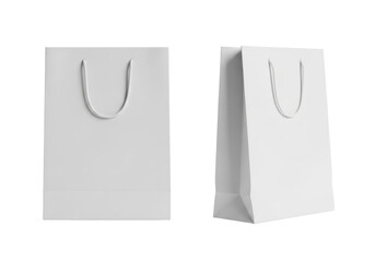 Two empty, transparent paper shopping bags, unbranded with white rope handles, one frontal, one 3/4 angle, on reflective surface against transparent studio backdrop with copy space, high-key