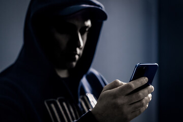 Phone and mobile hacker, thief and scammer. Protect digital data for scam, fraud or identity theft by cyber criminal. Crime with cellphone. Suspicious man in dark. Online romance fraudster.