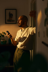 Man using cellphone indoors in warm evening light. 