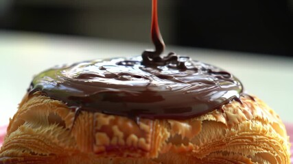 Thick chocolate sauce being poured onto a flaky golden croissant, creating a luscious topping - Powered by Adobe