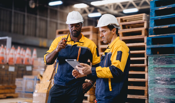 Distribution warehouse manager and client businesswoman using digital tablet checking inventory storage on shelf. Storehouse business worker and logistic engineer standing together at storage service