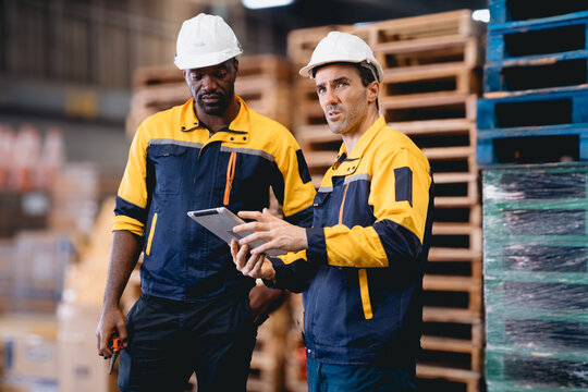 Distribution warehouse manager and client businesswoman using digital tablet checking inventory storage on shelf. Storehouse business worker and logistic engineer standing together at storage service