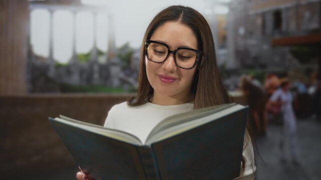 Young hispanic woman reading large book and smiling outdoors at roman ruins with oversized glasses and long hair; serenity knowledge culture exploration.