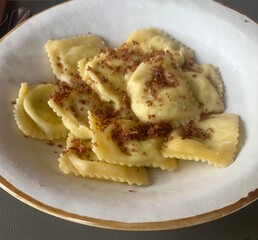 Closeup image of a plate of tortelli pasta filled with asparagus and topped with cured ham
