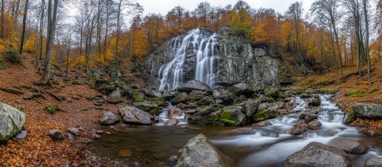 Cascading waterfall amidst autumn foliage in forested landscape setting