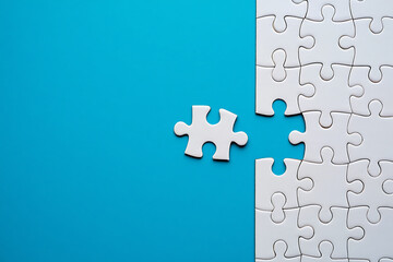 Fototapeta premium Single white puzzle piece floating near incomplete white puzzle