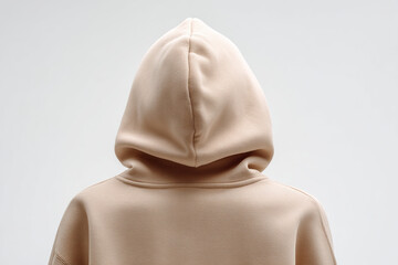 Back view of a person wearing a light tan or beige hooded sweatshirt against a plain white background. Style and Comfort.