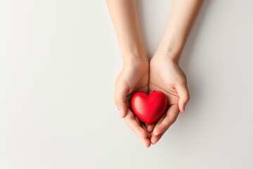 Fototapeta premium Faceless hands gently holding red heart shape, white background, concept of emotional care, therapy and support.