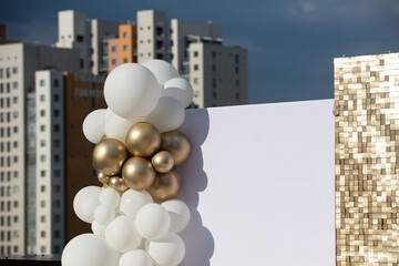 Photo zone decorated with gold and white balloons.