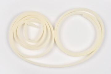 This image shows beige foam tape shaped into two irregular circular outlines, laid on a white...