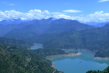 Obraz premium Tehri Lake, nestled in the Garhwal Himalayas of Uttarakhand, is a stunning man-made reservoir created by the Tehri Dam. Surrounded by lush green hills and snow-capped peaks.