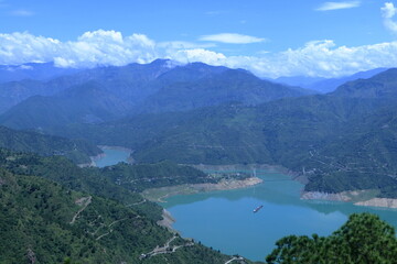 Obraz premium Tehri Lake, nestled in the Garhwal Himalayas of Uttarakhand, is a stunning man-made reservoir created by the Tehri Dam. Surrounded by lush green hills and snow-capped peaks.