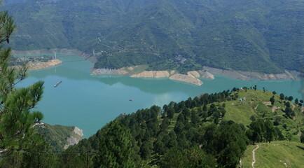 Fototapeta premium Tehri Lake, nestled in the Garhwal Himalayas of Uttarakhand, is a stunning man-made reservoir created by the Tehri Dam. Surrounded by lush green hills and snow-capped peaks.
