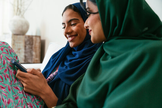 Emirati women sharing a moment of joy while using a smartphone at home