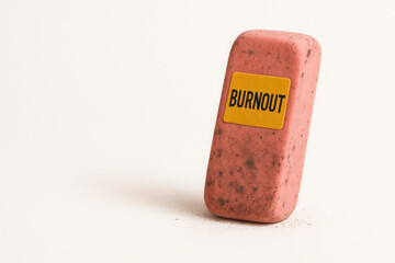 Pink eraser with yellow BURNOUT sticker on a light background. Space for text.