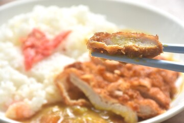 Tonkatsu crispy fried pork slice topping plain rice dressing potato and carrot in Japanese curry on plate 