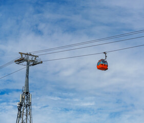cabins of funicular, cable car, against background of blue sky with white clouds