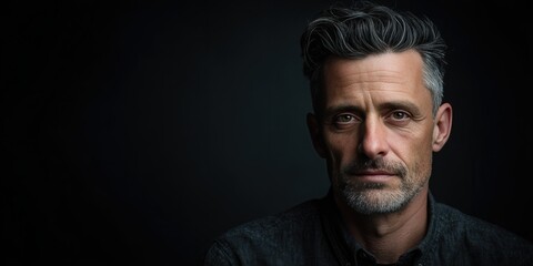 Fototapeta premium Confident Middle-Aged Man with Stylish Hair Against a Dark Background