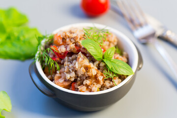 Cooked buckwheat with vegetables on a gray background. Simple dinner