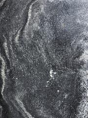 Close-up texture of dark stone or marble surface with natural white veining and patterns. Abstract mineral background, perfect for use in design, interiors, architecture, and as a high-resolution 