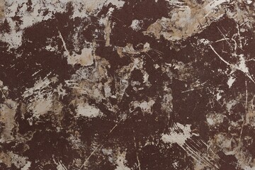 Abstract texture of a dark brown surface heavily distressed with light beige and off-white paint...