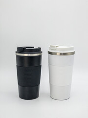 Two thermo mugs black and white with lids on a white background