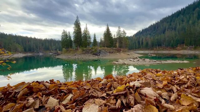 Lake Cauma with its crystal-clear, green water, which reflects the landscape on the calm surface of the water, framed by autumnal forests. Taken on an early morning without people at the lake.