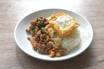 spicy stir fried slice beef meat with basil leaf and chili on rice topping egg in plate 