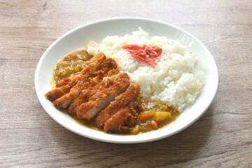 Tonkatsu crispy fried pork slice topping plain rice dressing potato and carrot in Japanese curry on plate 