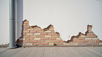 Fototapeta premium Peeling paint reveals brick wall underneath, showcasing texture and age. contrast between white surface and exposed bricks adds character