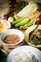 Shrimp paste chili dip, steamed rice, stir-fried morning glory with chili paste and omelet are placed on the dining table. Retro Thai style image.