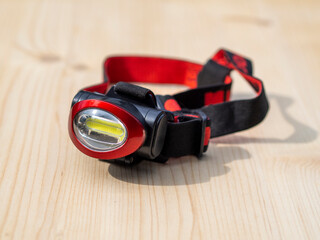 Headband led flashlight on a wooden background. Waterproof head torch that can be used in heavy rain. Perfect for a wide range of applications where effective hands-free lighting is required